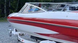 A red and white boat parked on gravel.